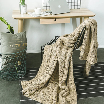DecorBites Khaki Beige Chunky Knit Wool Blanket draped over a chair in a cozy home office on Tampa Home & Garden Store