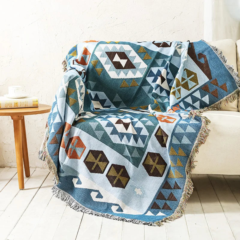 DecorBites knitted Nordic plaid blanket in teal blue with fringed edges on sofa on Tampa Home & Garden Store