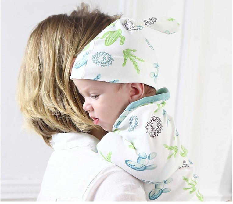 Stevvex baby swaddle blanket with cap in white with green-blue accents, infant in hooded wrap on Tampa Home & Garden Store