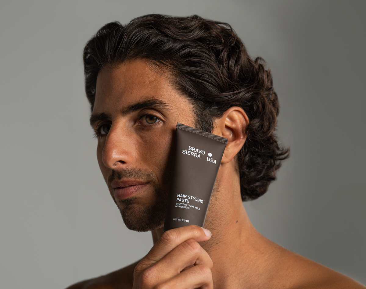 Hair styling paste tube by Bravo Sierra held against a man's jawline with dark wavy hair on Tampa Home & Garden Store