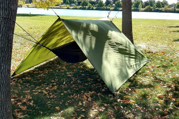 Hammock Rain Fly in olive green, pitched between trees above a hammock in a park on Tampa Home & Garden Store