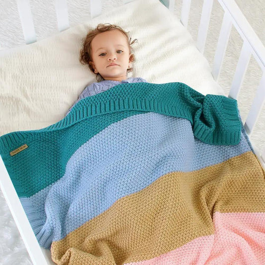 Stevvex baby knitted swaddle blanket in teal, blue, tan and pink, infant in crib on Tampa Home & Garden Store