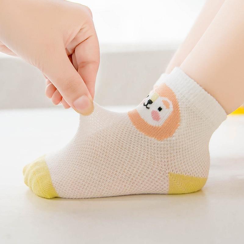 White baby sock with yellow toe and heel, cute face, breathable mesh knit being stretched on Tampa Home & Garden Store