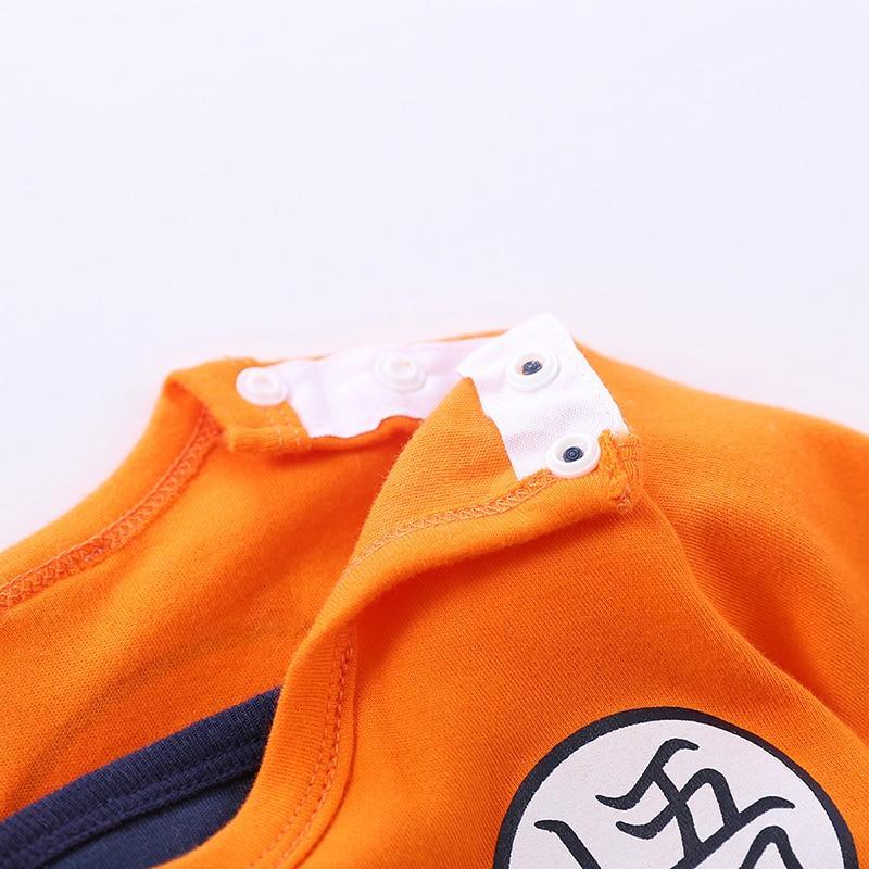 Orange baby romper onesie with shoulder snaps and navy trim featuring a dragon patch on front on Tampa Home & Garden Store
