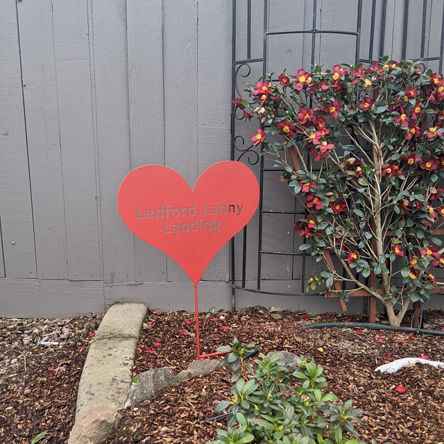 Heart garden stake rust-colored metal by Rustica Ornamentals in a garden scene on Tampa Home & Garden Store