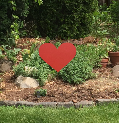 Red metal heart garden stake in a landscaped garden with mulch and rocks, Rustica Ornamentals on Tampa Home & Garden Store