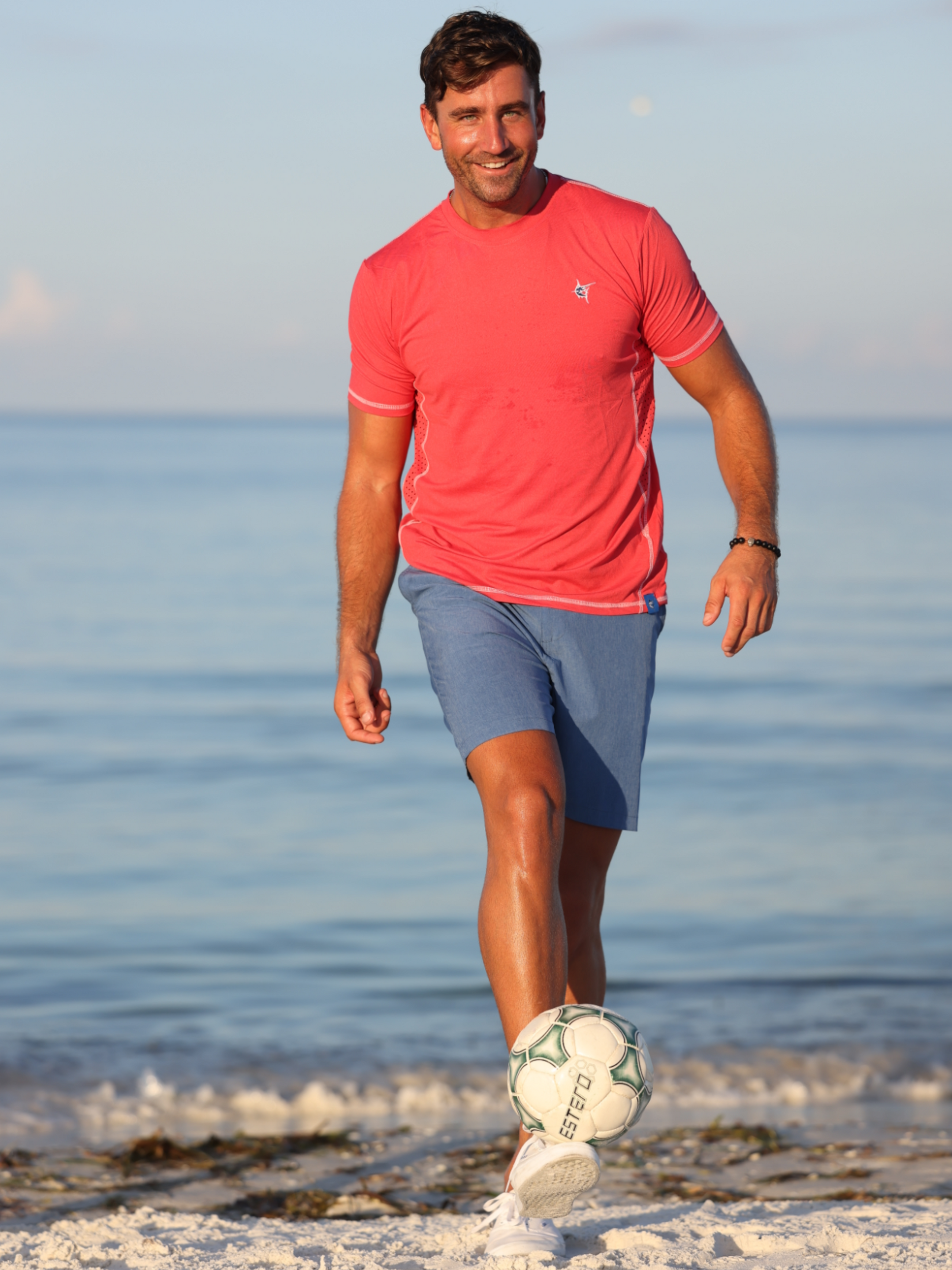 Grander Short Sleeve Performance Tee coral pink by White Water Life at the beach with a soccer ball on Tampa Home & Garden Store