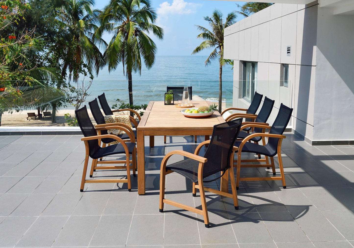 Rinjani rectangular wooden dining table with 8 Manhattan black armchairs on a seaside terrace on Tampa Home & Garden Store