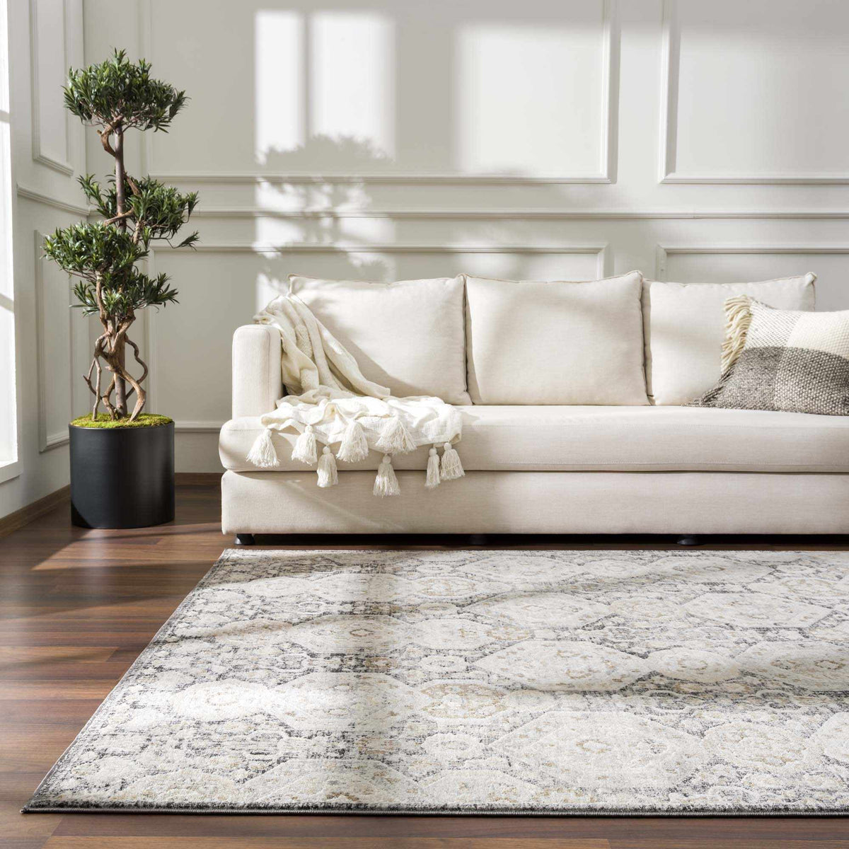 Minoa Area Rug by Boutique Rugs in ivory and gray with a distressed pattern under a cream sofa on Tampa Home & Garden Store
