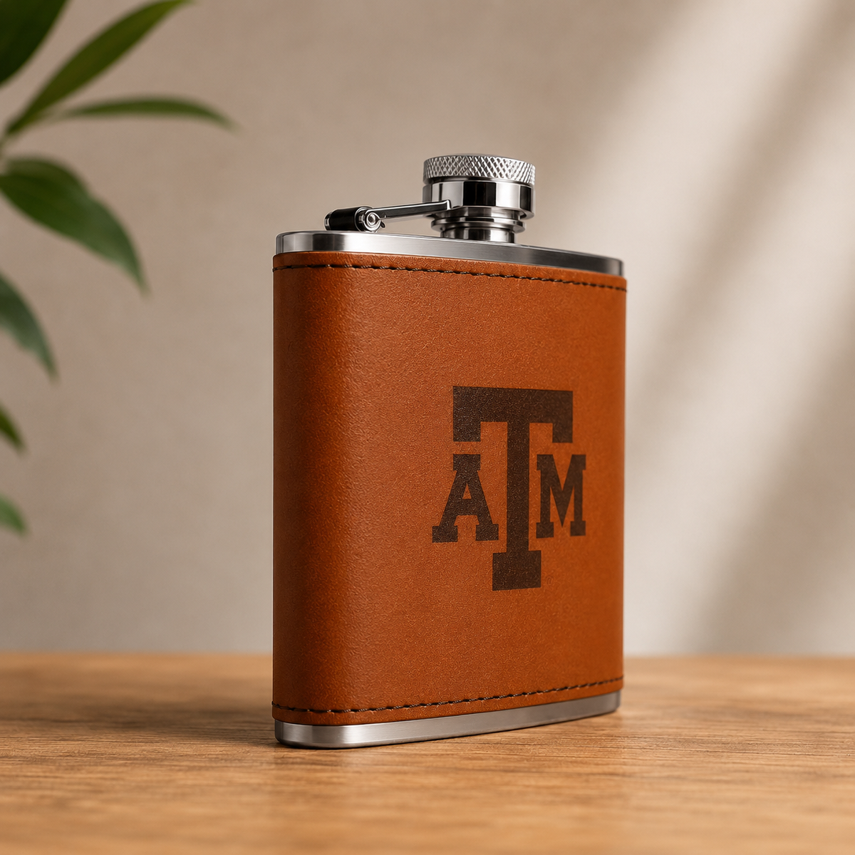 Texas A&M Leather Flask with tan leather wrap, silver cap and bottom, A&M monogram logo on Tampa Home & Garden Store