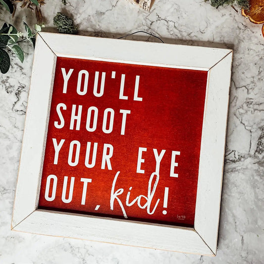 You'll Shoot Your Eye Out Sign by Gia Roma, red panel with white lettering in a white frame on Tampa Home & Garden Store
