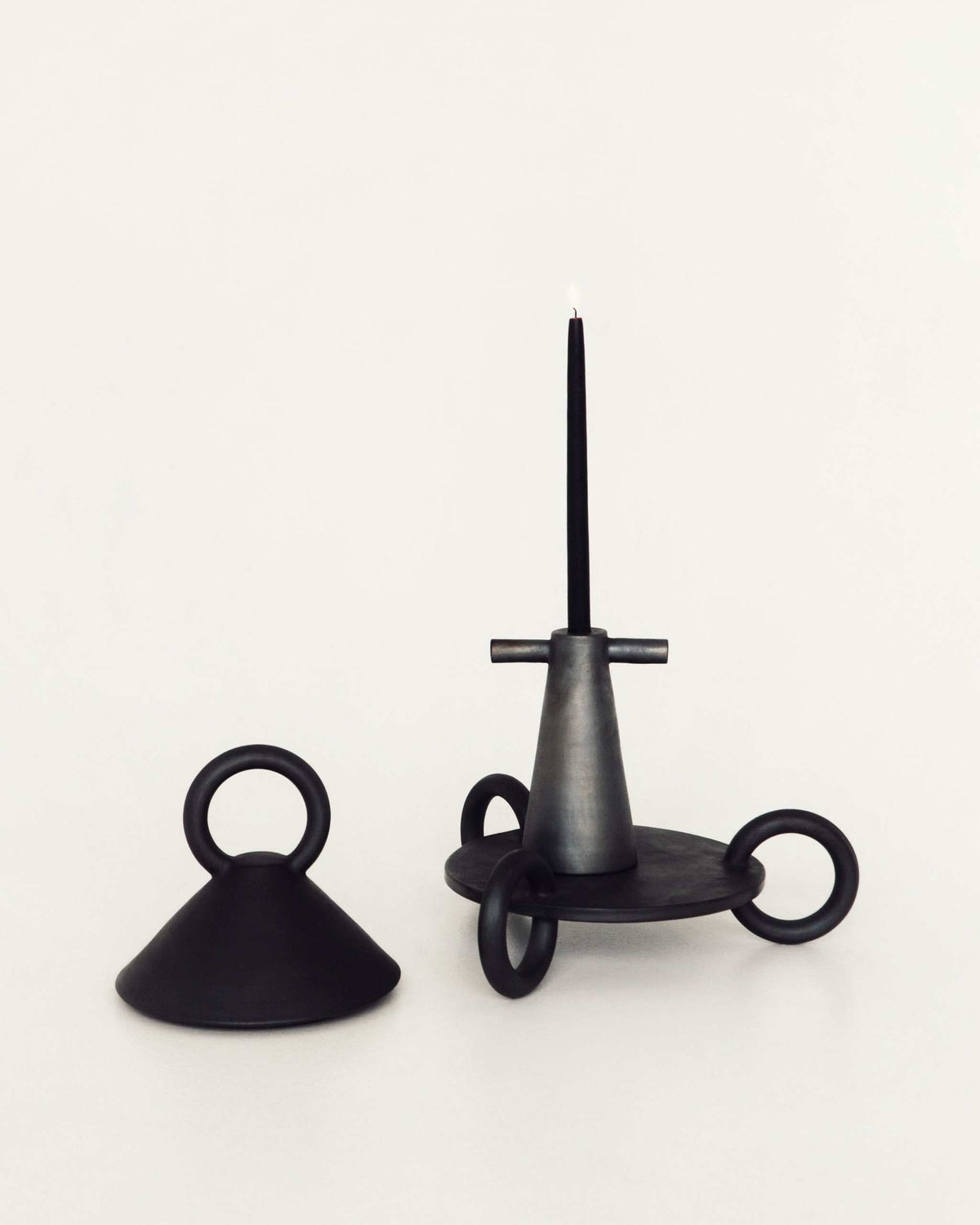 Black metal candle holder with tall central taper candle and looping arms, industrial style on Tampa Home & Garden Store
