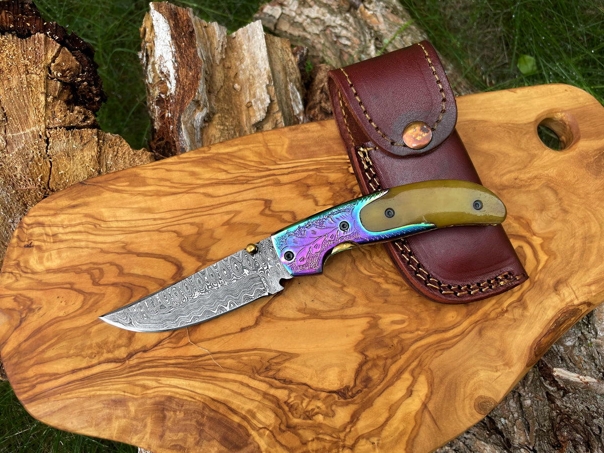 Damascus pocket knife with engraved bolster and rainbow blade, brown leather sheath on Tampa Home & Garden Store