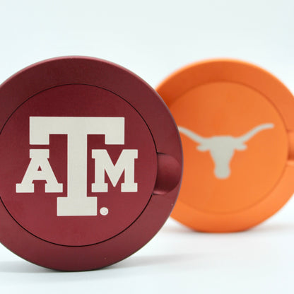 Texas A&M metal nicotine pouch cans lids in maroon and orange, close-up on Tampa Home & Garden Store