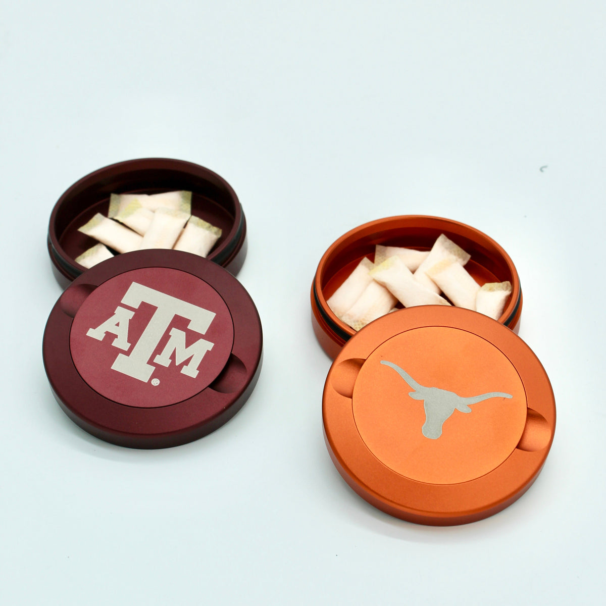 Two Texas A&M metal nicotine pouch cans with maroon A&M lid and orange longhorn lid on Tampa Home & Garden Store
