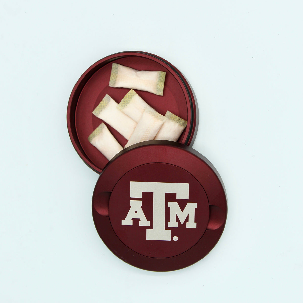 Texas A&M metal nicotine pouch cans, three red round tins with white A&M logo on Tampa Home & Garden Store