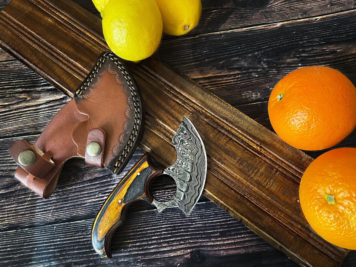 Titan Custom Alaskan Ulu style Damascus steel knife with leather sheath on dark wood surface on Tampa Home & Garden Store