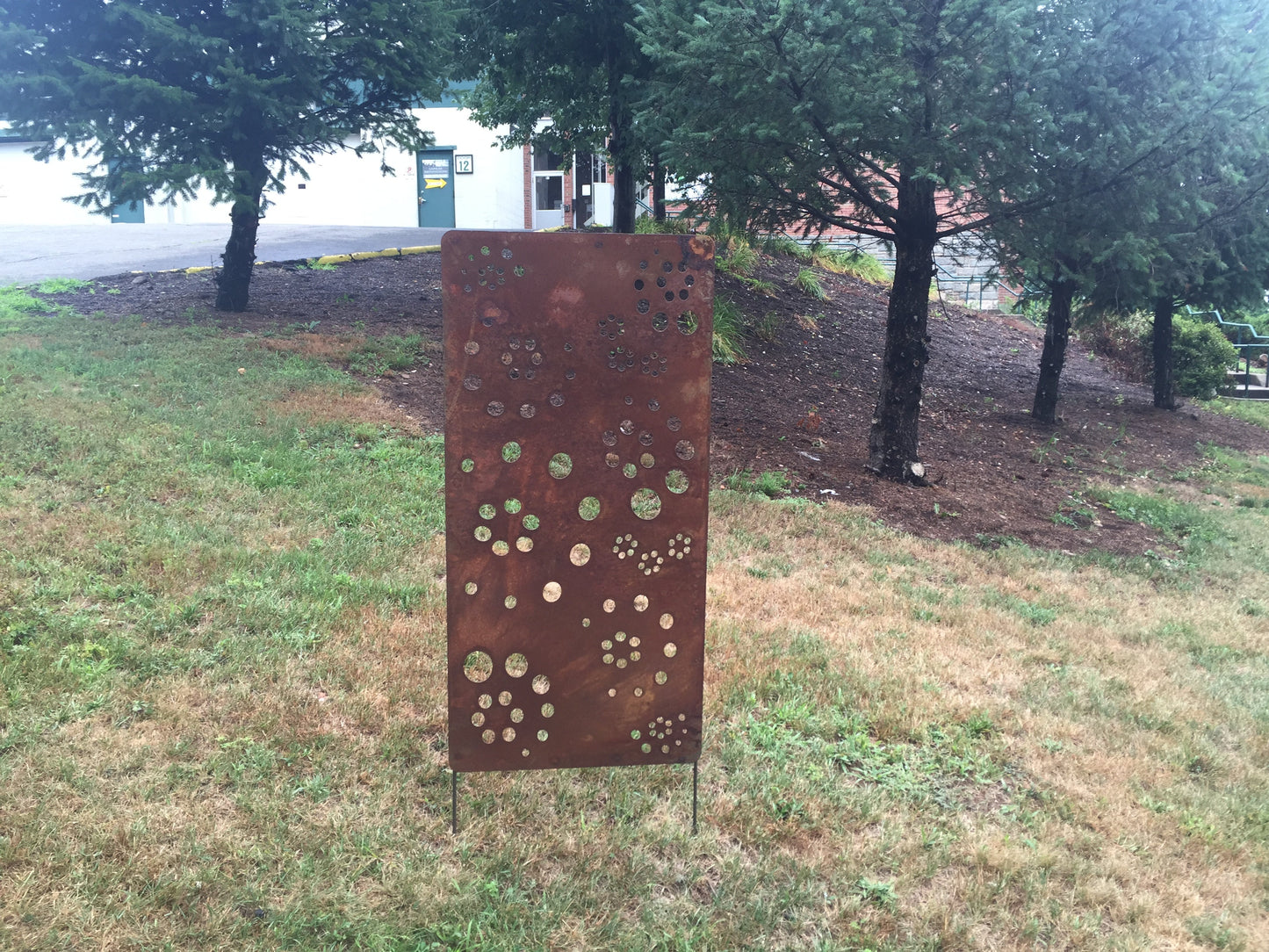 Metal privacy screen by Rustica Ornamentals, rusted perforated steel panel with circular cutouts on Tampa Home & Garden Store