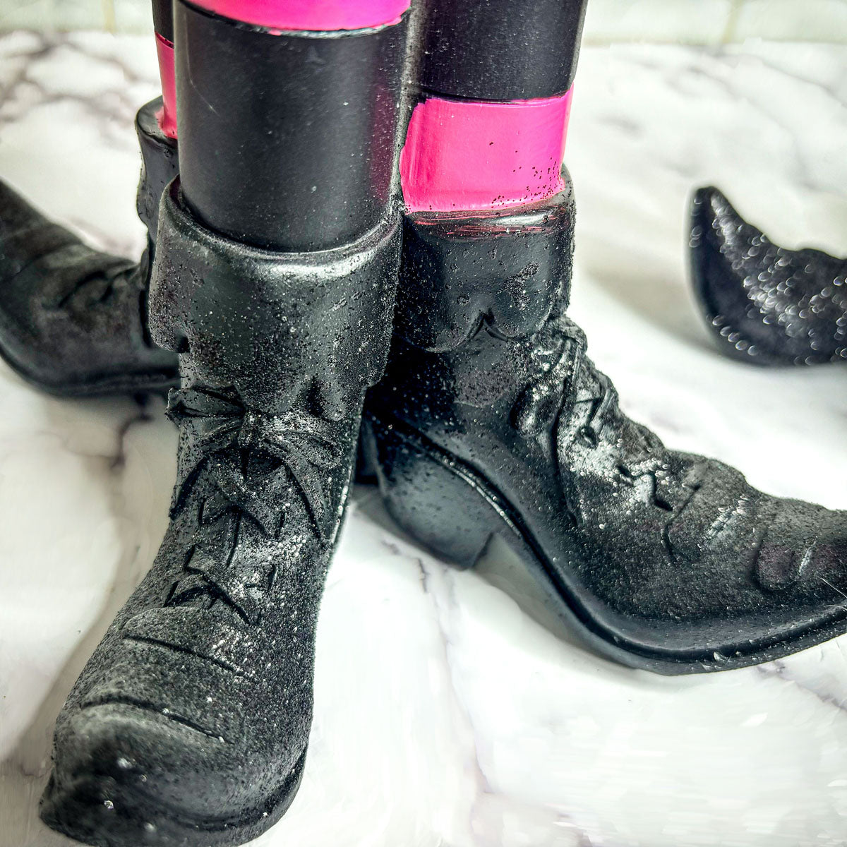 Wicked Witch Candle Holder: close-up of black lace-up boots with pink leg band and glittery dust on Tampa Home & Garden Store