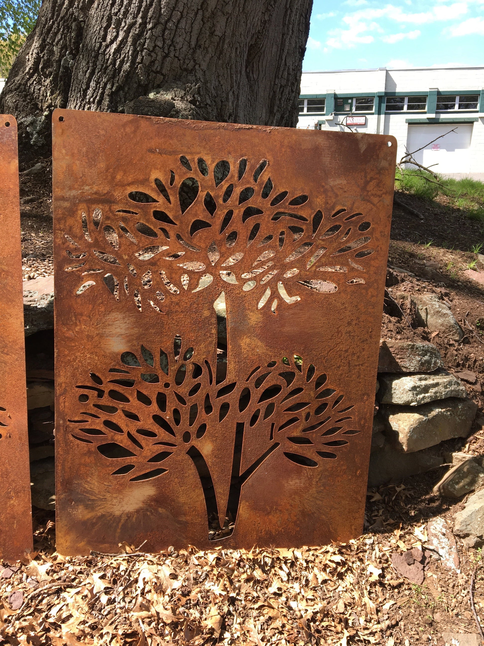Outdoor privacy screens pair with tree silhouette cutouts in rusted metal 46-inch panels on Tampa Home & Garden Store