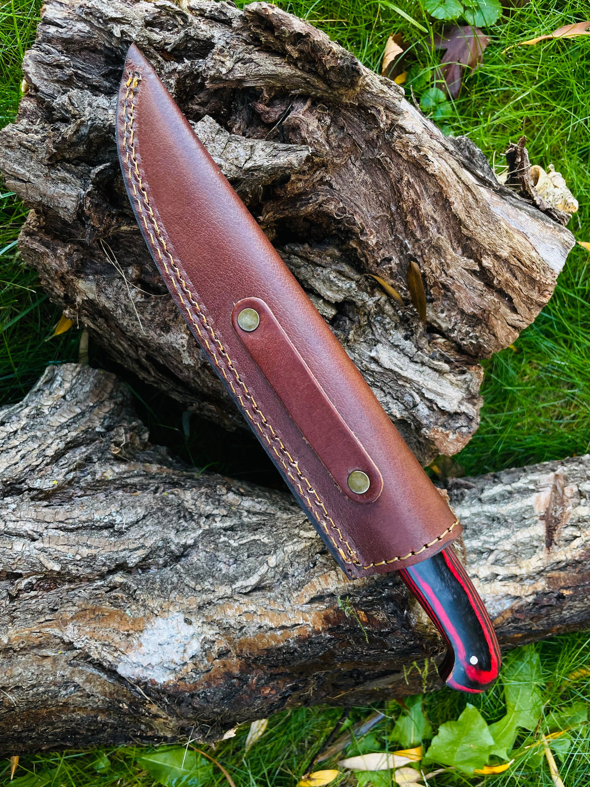 Damascus Steel Custom Flay Knife TK-050 in brown leather sheath with brass rivets on a log on Tampa Home & Garden Store