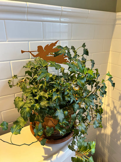 Angel plant stake in rust-orange metal with trumpet-playing silhouette among ivy on Tampa Home & Garden Store