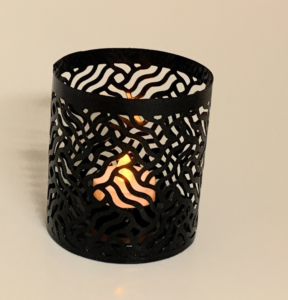 Vibhsa votive candle holder, black laser-cut metal cylinder with warm candlelight on Tampa Home & Garden Store