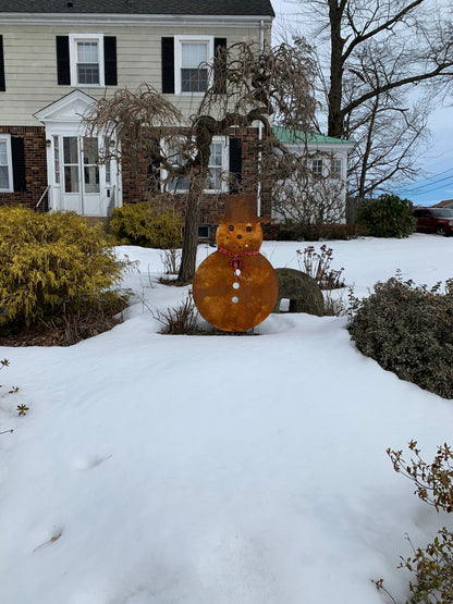 Large rust-orange outdoor snowman sculpture with top hat and red scarf in snowy front yard on Tampa Home & Garden Store