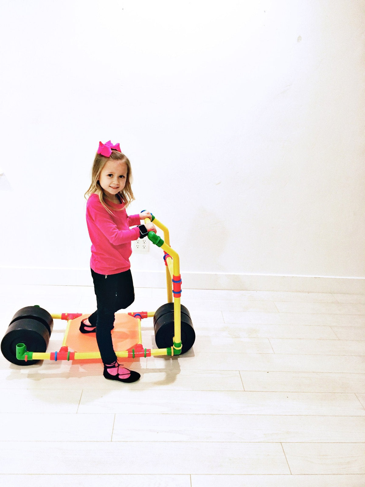 TubeLox Deluxe Set 2x STEM toy; ride-on frame with yellow bars and wheels; child nearby on Tampa Home & Garden Store
