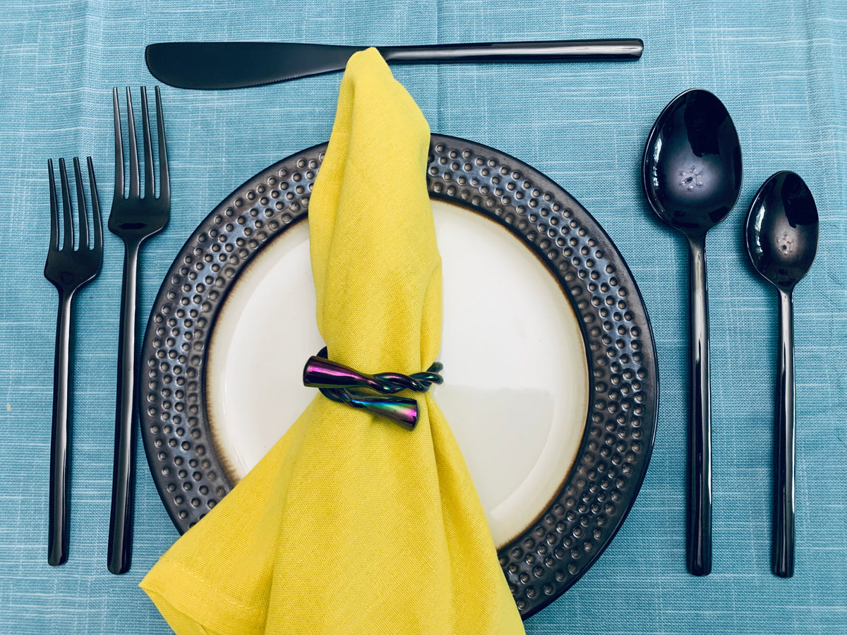 Vibhsa black stainless steel flatware set, 20 pc, arranged with yellow napkin on blue table on Tampa Home & Garden Store