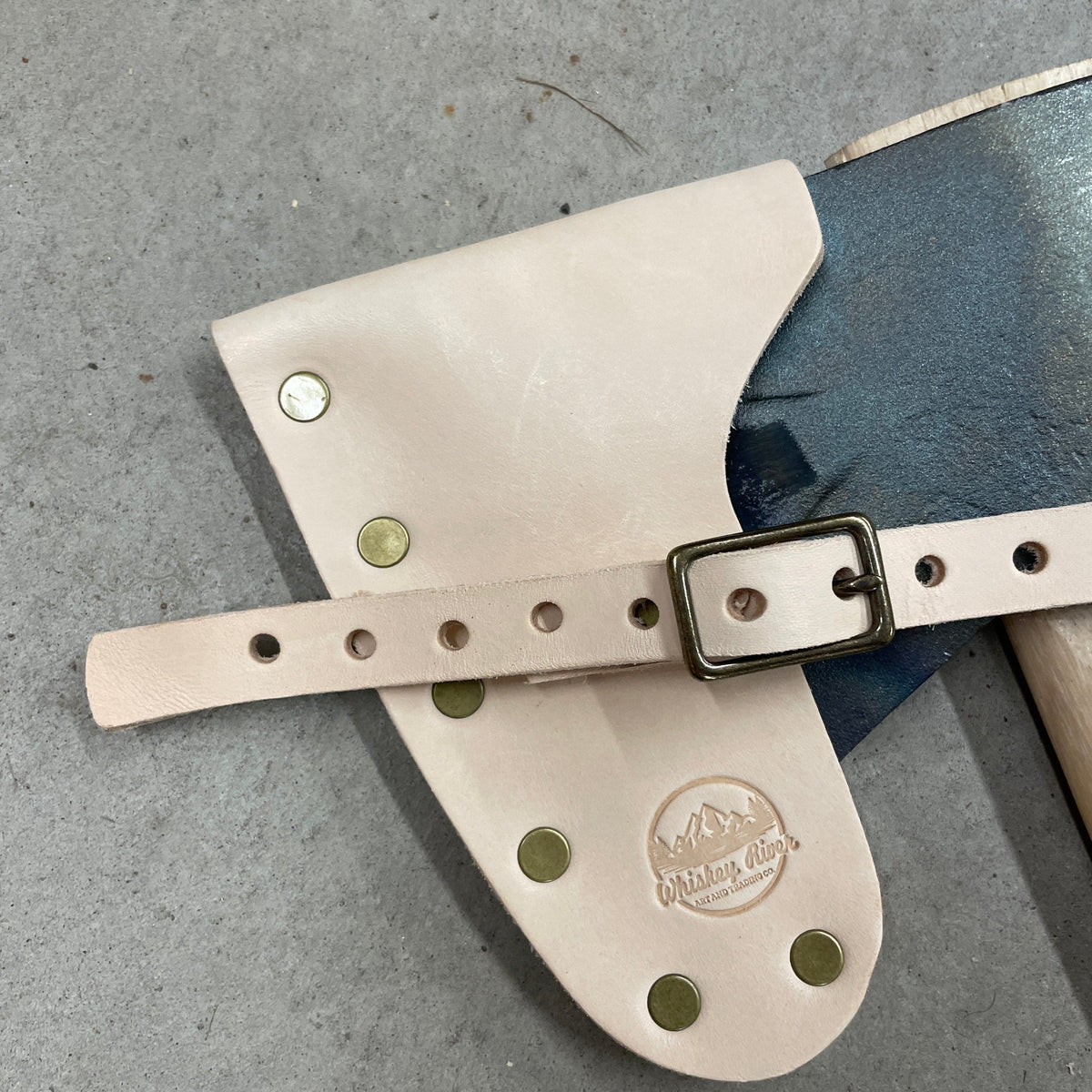 Leather belt strap with brass rivets and metal buckle; tan leather with Whiskey River logo on Tampa Home & Garden Store