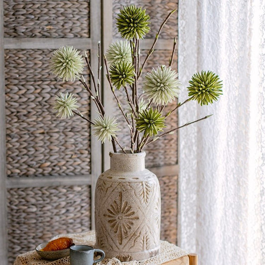 Round green ball artificial flowers on twig stems in a rustic ceramic vase on Tampa Home & Garden Store