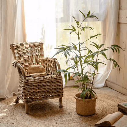 Artificial Bamboo Leaves in Pot green faux bamboo plant in woven planter beside wicker chair on Tampa Home & Garden Store