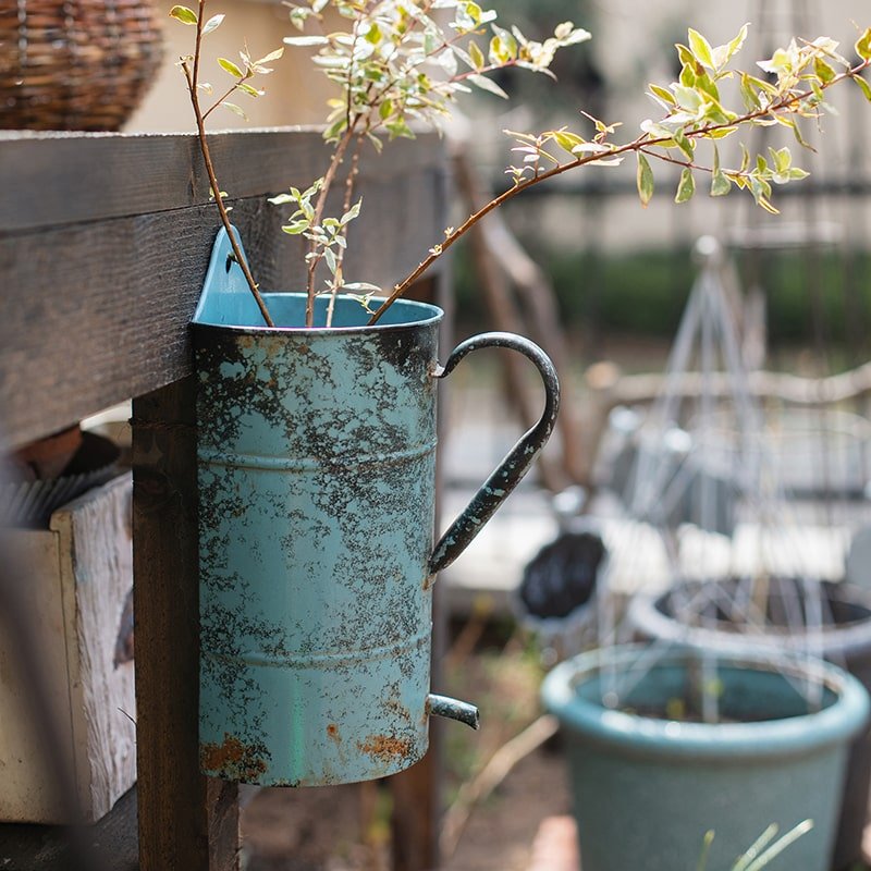 Rustic blue iron flower pot with handle mounted on a wooden fence, weathered turquoise patina on Tampa Home & Garden Store