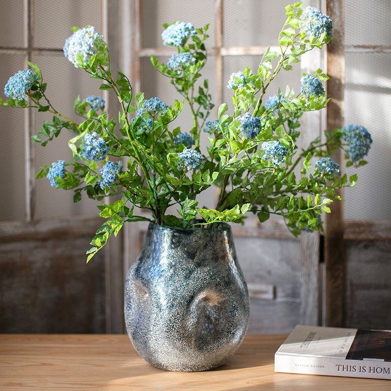 Blue Bubble Hand Blown Glass Vase by RusticReach with green foliage and blue flower clusters on Tampa Home & Garden Store
