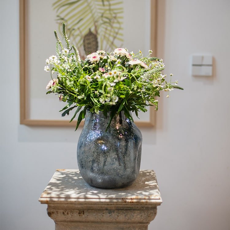 Blue bubble hand blown glass vase by RusticReach holding a bouquet of white daisies and greenery on Tampa Home & Garden Store