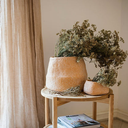 Two cement weaving pattern planters in terracotta tones with dried flowers on a wooden table on Tampa Home & Garden Store