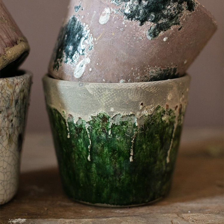 Colorful terracotta pots with green glaze dripping, stacked with a mossy-toned pot on Tampa Home & Garden Store