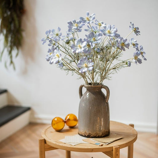 Faux Silk Cosmos Stem Blue 24in Tall RusticReach arranged in a brown ceramic pitcher on a round wooden table on Tampa Home & Garden Store