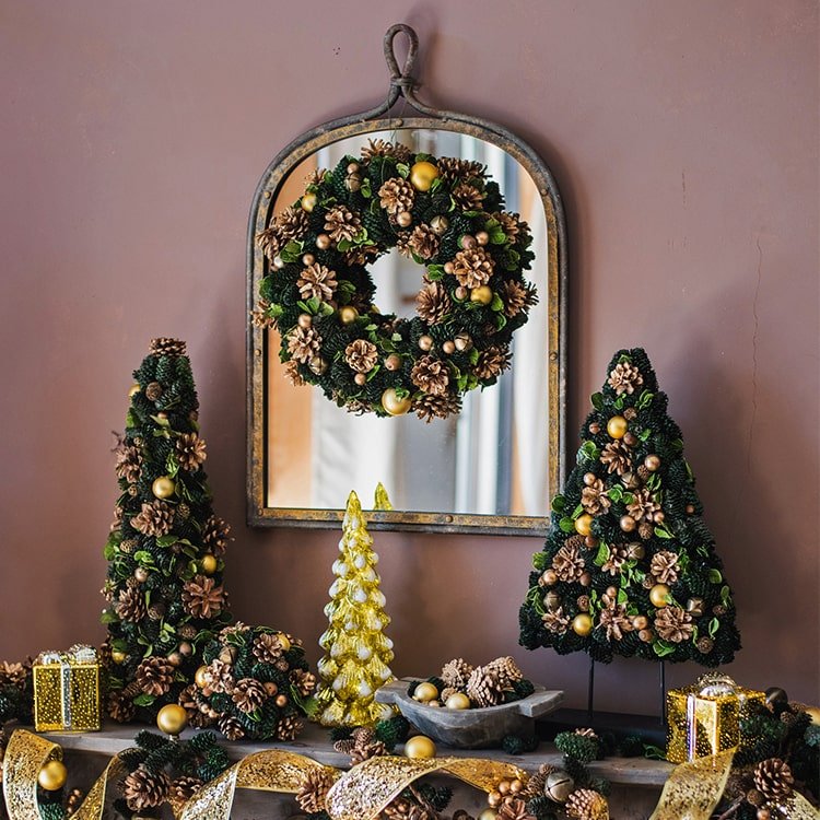Antique Style Dark Iron Mirror with rustic finish flanked by pinecone wreaths and gold accents on Tampa Home & Garden Store