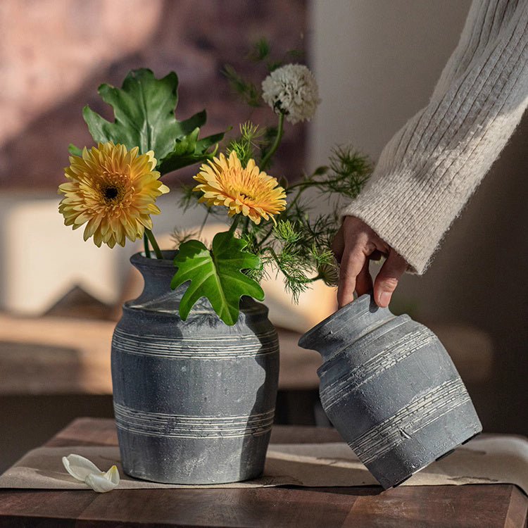 Two RusticReach gray clay pottery vases with striped bands, one holding yellow flowers on Tampa Home & Garden Store