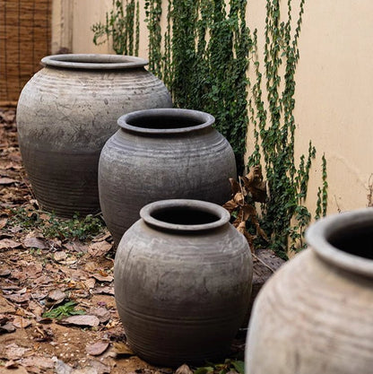 Large antique ceramic planters, four gray-toned pots arranged along a wall by ivy on Tampa Home & Garden Store