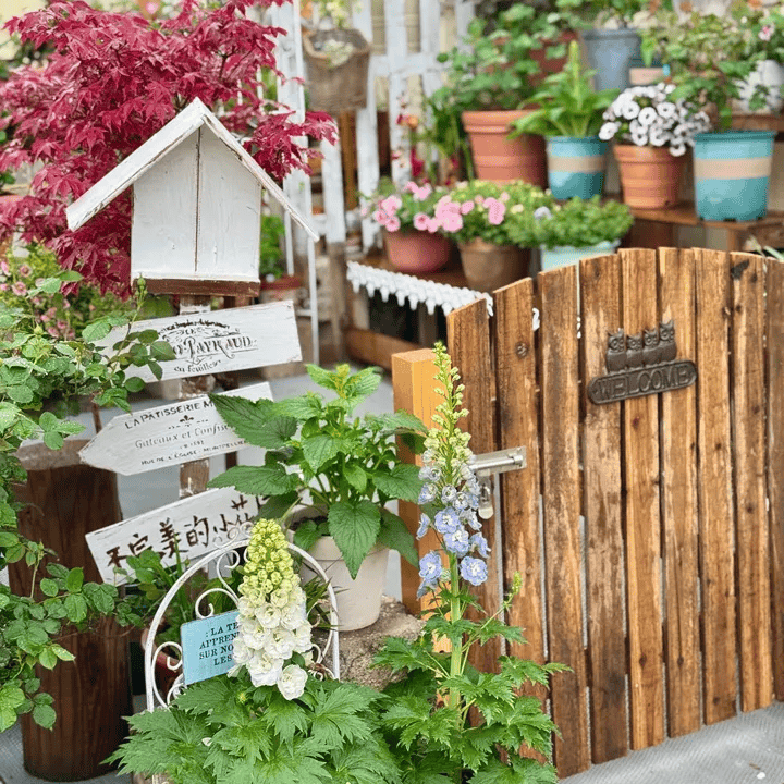 Four Owls Cast Iron Welcome Sign by RusticReach in a rustic garden with a wooden gate on Tampa Home & Garden Store