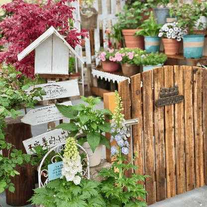 Four Owls Cast Iron Welcome Sign by RusticReach in a rustic garden with a wooden gate on Tampa Home & Garden Store