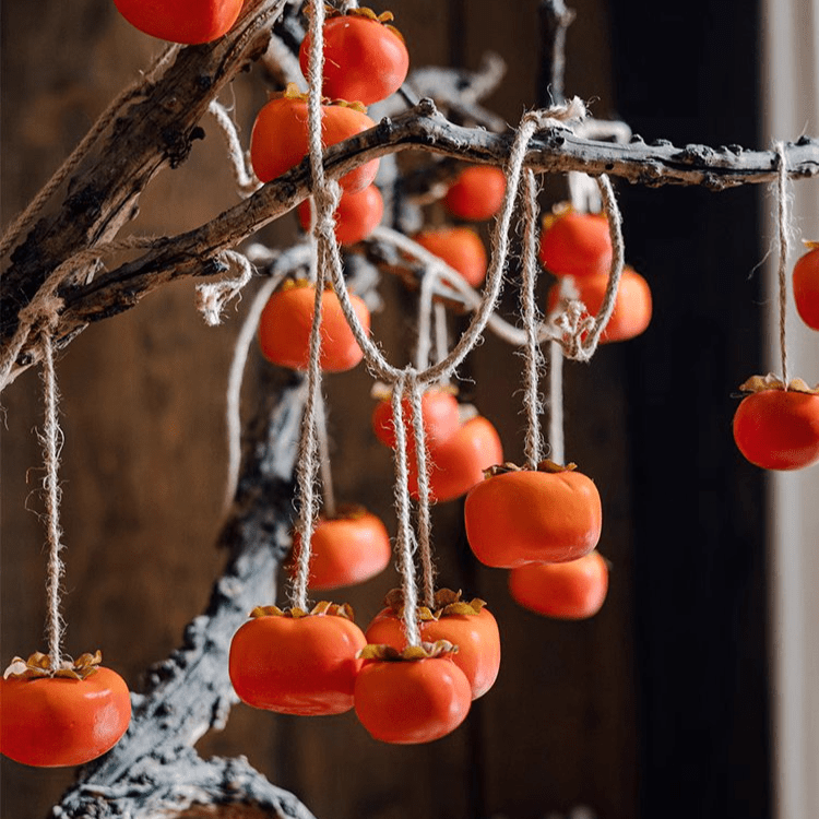 Artificial persimmon fruit string decor with orange fruits on twine hanging from a branch on Tampa Home & Garden Store
