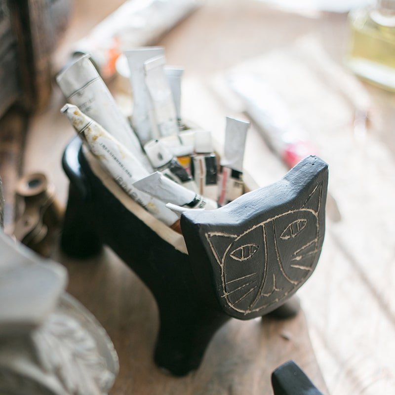 Cat shape concrete planter, black with etched face, holds rolled newspaper on Tampa Home & Garden Store