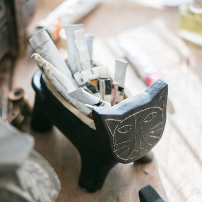 Cat shape concrete planter, black with etched face, holds rolled newspaper on Tampa Home & Garden Store