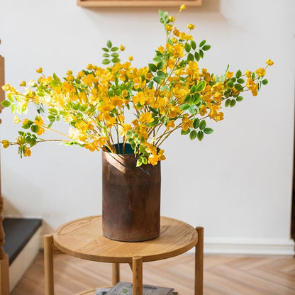 Rust Style Art Glass Vase dark bronze patina metal with bright yellow blossoms on a round wood table on Tampa Home & Garden Store