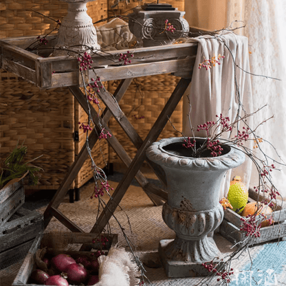 Rustic artificial red berry vine, 63in long, RusticReach decor draped over a weathered urn and table on Tampa Home & Garden Store