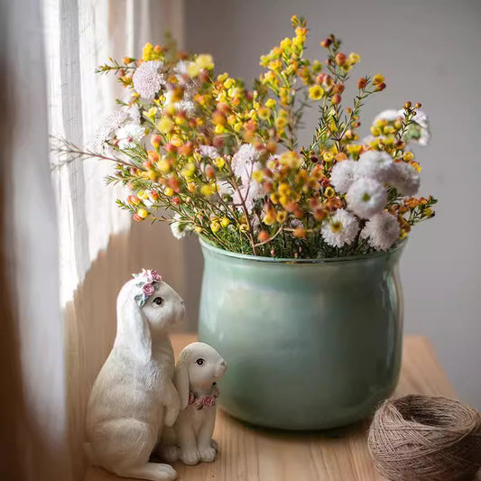 Ruhai Low Glass Vase in muted green with yellow and white flowers; two rabbit figurines nearby on Tampa Home & Garden Store